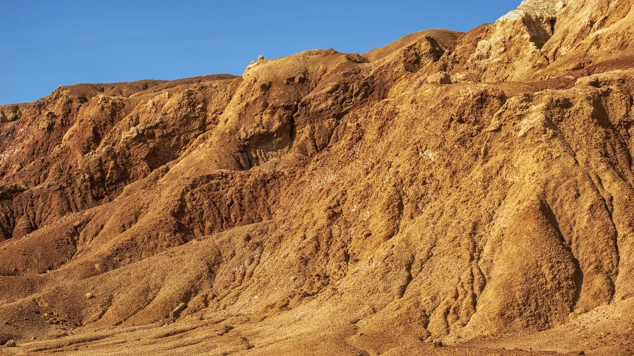 Open pit quarry bench where a wheeled portable crushing station reduces blasted rock